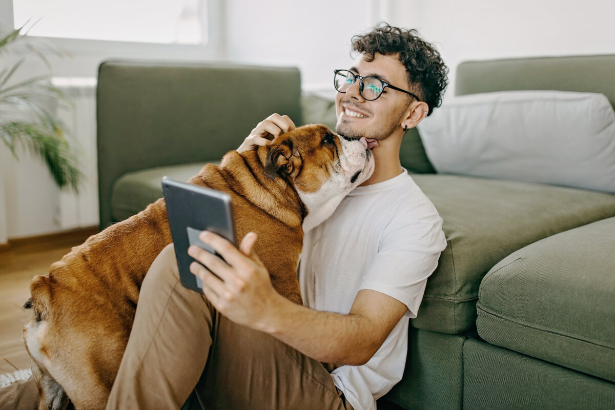 Zillow user sitting on the floor with a dog while holding a tablet.