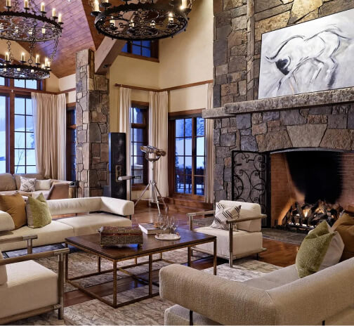 Spacious living room with a large stone fireplace and snowy views outside.