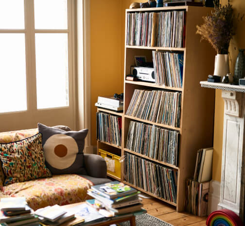 Cozy living room with a bookshelf filled with vinyl records next to a couch.